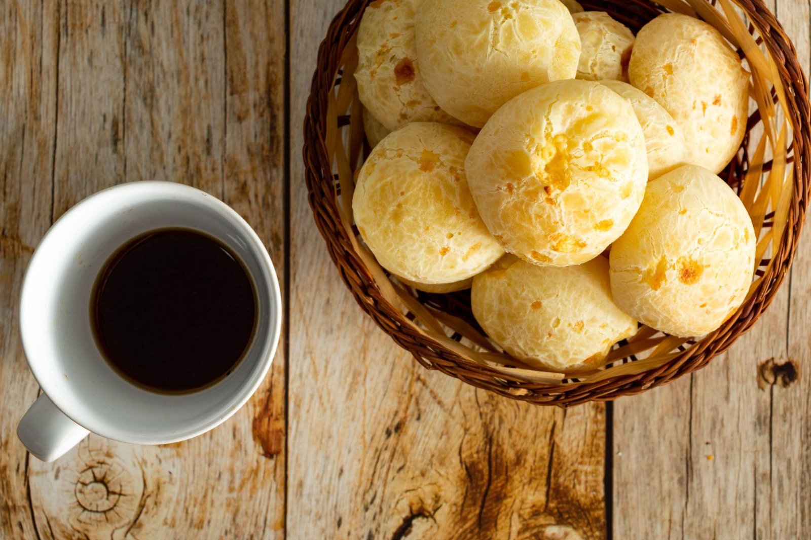 Pão de queijo caseiro servido com uma xícara de café.